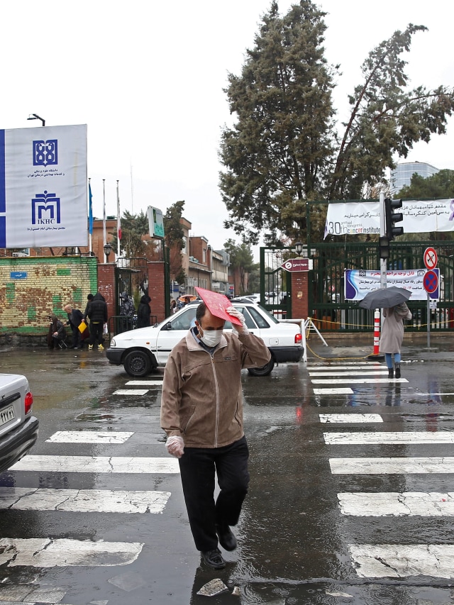 Warga Iran mengenakan masker untuk mencegah tertularnya virus corona, ketika berjalan di jalan di Teheran, Iran. Foto: WANA/Nazanin Tabatabaee via REUTERS