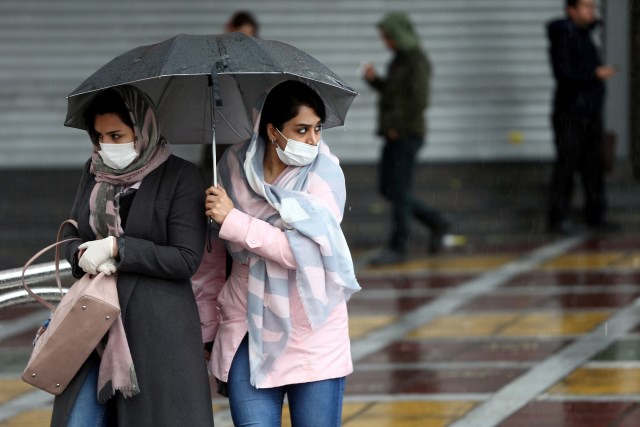 Masyarakat Iran mengenakan masker untuk mencegah tertularnya virus corona, ketika berjalan di jalan di Teheran, Iran. Foto: WANA/Nazanin Tabatabaee via REUTERS