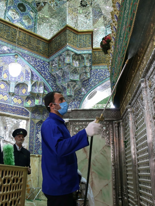 Seorang pekerja mendisinfeksi situs suci Masumeh Qom untuk mencegah penyebaran virus corona di Iran. Foto: AFP/FARS NEWS AGENCY/MEHDI MARIZAD