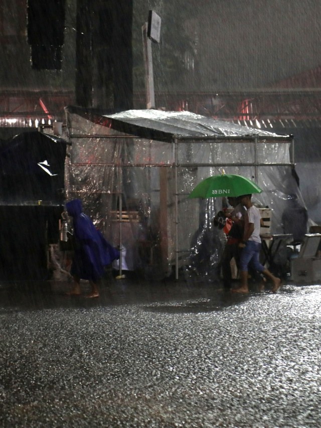 Sejumlah pengunjung mengenakan jas hujan dan payung melintas di tengah hujan saat BNI Java Jazz Festival 2020, di JIExpo Kemayoran, Jakarta, Minggu (1/3/2020). Foto: Nugroho Sejati/kumparan