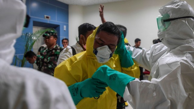 Persiapan petugas dengan pakaian pelindung lengkap saat menyambut kedatangan kru kapal pesiar Diamond Princess. Foto: ANTARA FOTO/Muhammad Adimaja