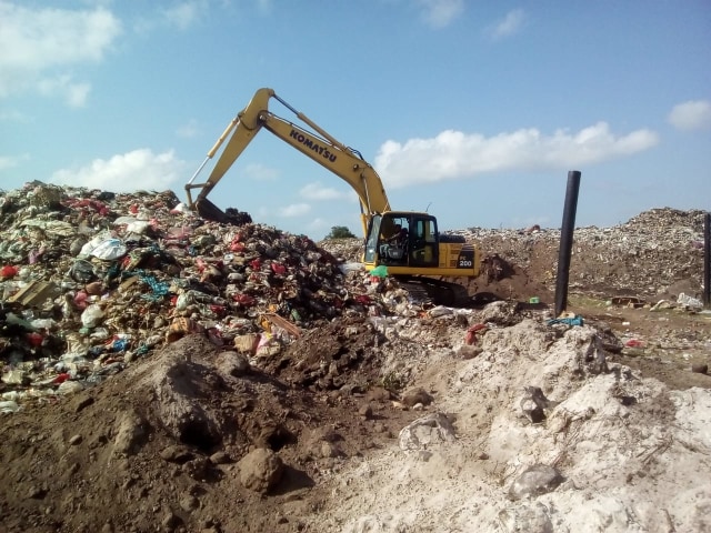 Alat berat sedang bekerja memilah sampah rumah tangga yang menumpuk di TPA.