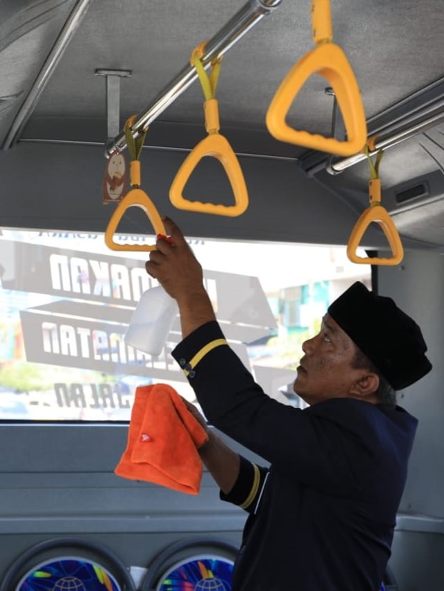 Seorang pramugara bus Trans Koetaradja membersihkan pegangan gantung yang sering disentuh oleh penumpang. Foto: Irfan Fuadi-Humas Dishub Aceh