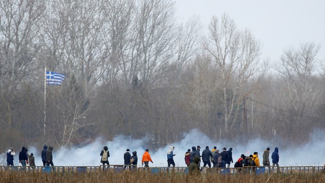 Para migran berjalan di dekat gas mata air di perbatasan Turki dan Yunani di Edirne, Turki. Foto: REUTERS / Huseyin Aldemir