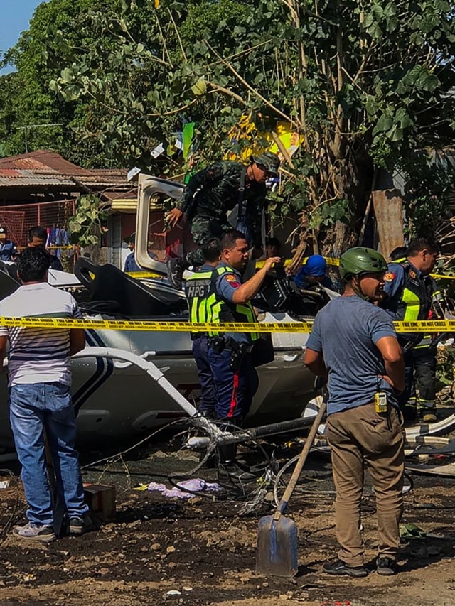 Petugas penyelidik berada di sekitar puing-puing helikopter lonceng 429 yang ditumpangi Kepala Polisi Filipina jatuh di kota San Pedro, Laguna, Filipina. Foto: DANTE PERALTA / AFP