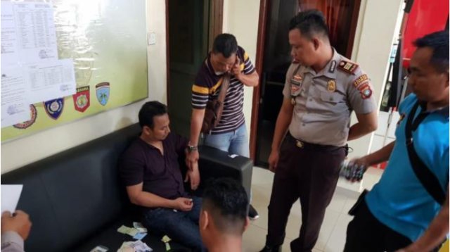 Herman (duduk) saat diperiksa polisi di Mapolsek Meral. (Foto: Edo/Batamnews)