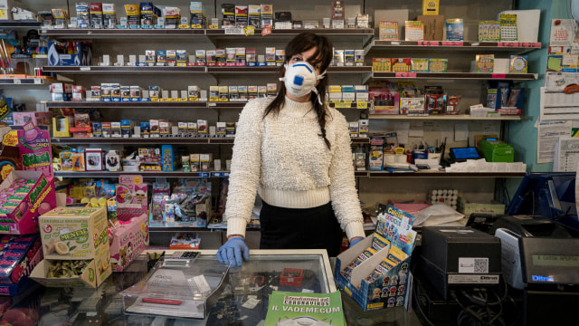 Penjaga mini market di San Fiorano, Italia menggunakan masker untuk mencegah penularan virus corona. Foto: Marzio Toniolo/via REUTERS