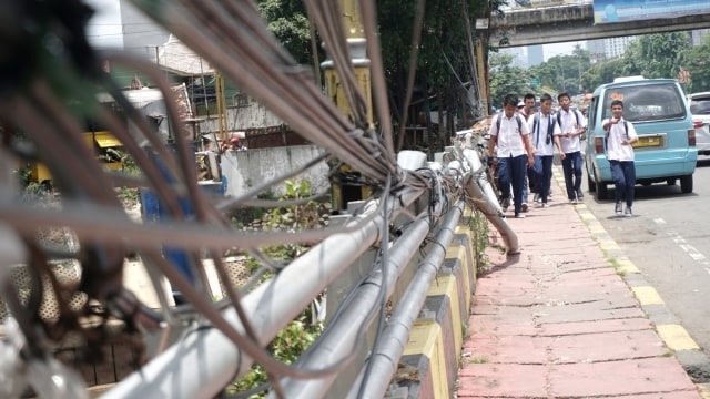 Sejumlah pelajar melintas di sekitar lokasi kabel listrik yang menjuntai di trotoar di kawasan Bukit Duri, Jakarta Timur (10/3). Foto: Iqbal Firdaus/kumparan