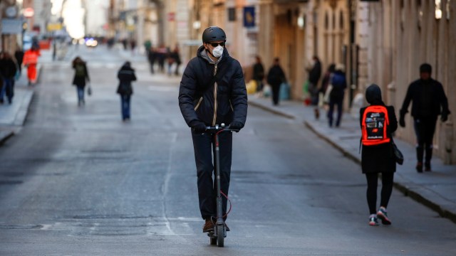 Pengendara skuter listrik melintasi jalanan yang sepi di Roma, Italia. Foto: REUTERS/Remo Casilli