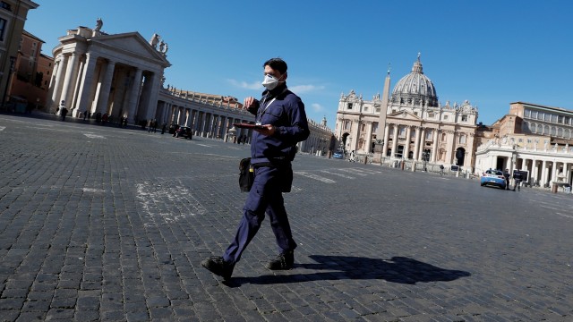 Seorang pria berjalan melewati Lapangan Santo Petrus, di Kota Roma, Italia. Foto: REUTERS/Guglielmo Mangiapane