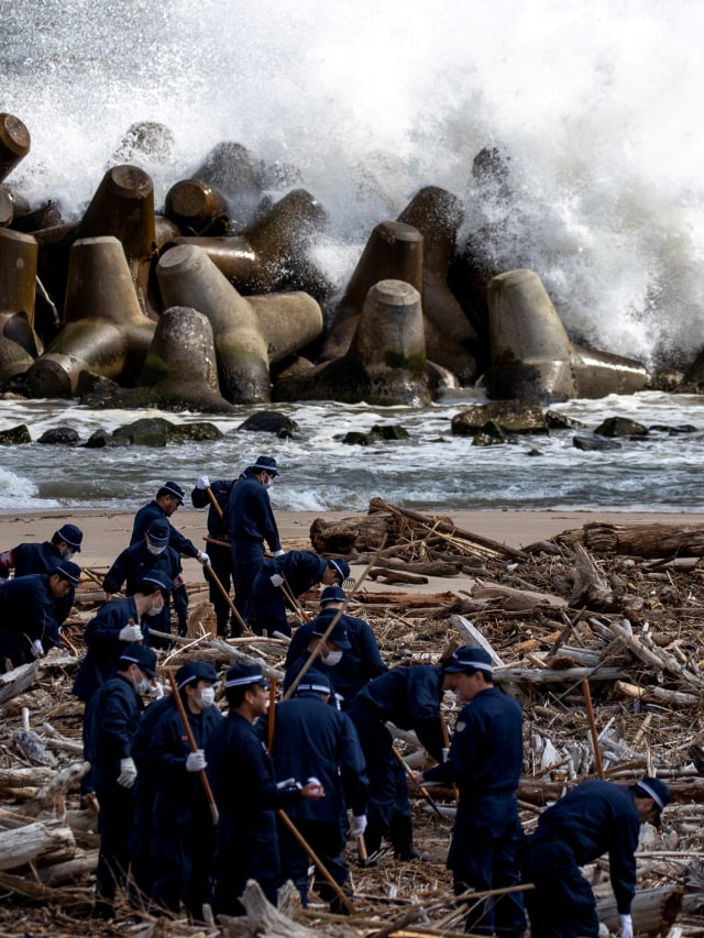 Polisi mencari sisa-sisa orang yang hilang setelah gempa bumi dan tsunami 9 tahun lalu di Namie, prefektur Fukusima, Jepang, Rabu (11/3). Foto: REUTERS/Athit Prawongmetha