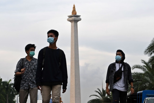 Sejumlah warga dengan menggunakan masker berjalan di kawasan Monumen Nasional, Jakarta, Rabu (11/3). Foto: ANTARA FOTO/Aditya Pradana Putra