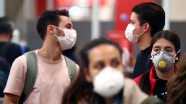 Penumpang menggunakan masker antisipasi wabah virus corona saat berada di Bandara Adolfo Suarez Barajas di Madrid, Spanyol.  Foto: REUTERS / Sergio Perez