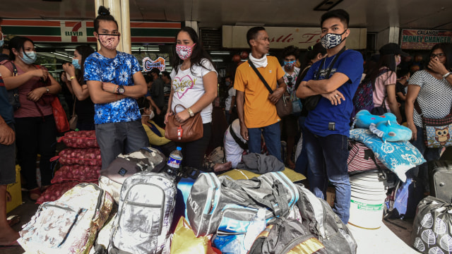 Penumpang mengenakan masker saat menunggu di Terminal Bus Pusat Araneta di Cubao di Manila, Filipina, Jum'at (13/3).  Foto: AFP/Maria Tan