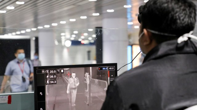 Petugas kesehatan Malaysia memeriksa penumpang dengan thermal scanner saat tiba di Bandara Internasional Kuala Lumpur, Malaysia. Foto: REUTERS / Lim Huey Teng