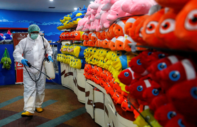 Petugas dengan baju hazmat menyemprotkan desinfektan di sekitar toko souvenir Sea World, Ancol, Jakarta, Indonesia, Sabtu (14/3). Foto: REUTERS/Ajeng Dinar Ulfiana