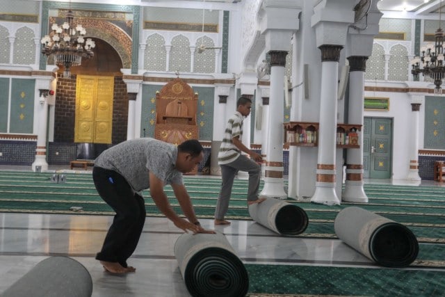 Petugas Masjid Raya Baiturrahman di Aceh saat menggulung ambal/karpet masjid. Foto: Suparta/acehkini