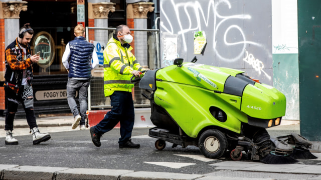 Seorang pembersih jalan memakai topeng pelindung saat membersihkan Jalan Grafton di pusat Kota Dublin, Irlandia, Jumat (13/3). Foto: PAUL FAITH / AFP