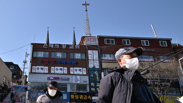 Pejalan kaki memakai masker di depan Gereja Grave River di Seongnam, Korea Selatan. Foto: AFP/JUNG YEON-JE