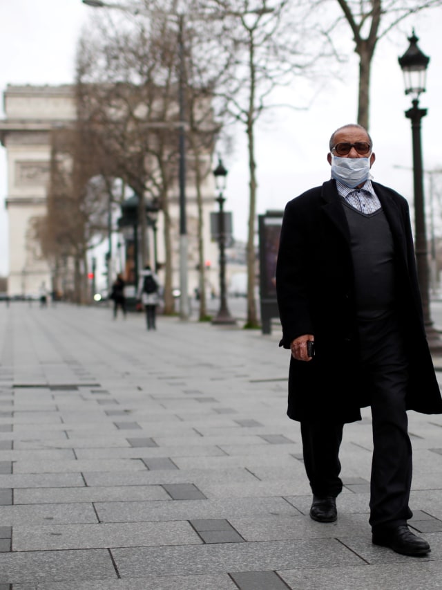 Warga menggunakan masker berjalan di Champs Elysees Avenue, Paris, Prancis.  Foto: REUTERS / Gonzalo Fuentes