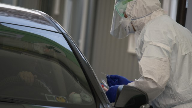 Petugas kesehatan menggunakan pakaian pelindung memeriksa kendaraan di pusat pengujian drive-through, Seoul, Korea Selatan. Foto: AFP/ Ed JONES