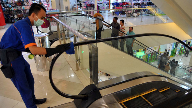 Pekerja membersihkan pegangan tangan tangga jalan dengan cairan disinfektan di pusat perbelanjaan Cibinong City Mall, Kabupaten Bogor, Jawa Barat, Sabtu, (14/3) Foto: ANTARA FOTO/Arif Firmansyah