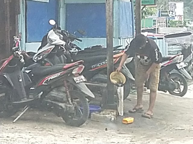 Salah satu Karyawan bengkel Karla saat buang oli sisa ke dalam pipa, foto BLH Manokwari