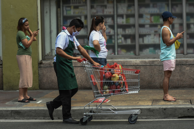Sejumlah warga tampak mengenakan masker dan menjaga jarak saat mengantre di supermarket di Manila, Filipina, Selasa (17/3). Foto: AFP/Maria Tan