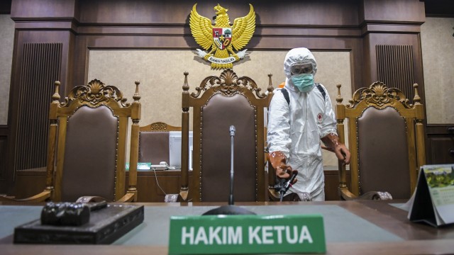 Petugas PMI Kota Jakarta Pusat menyemprotkan cairan disinfektan di ruangan sidang Pengadilan Tipikor, Jakarta, Rabu (18/3/2020). Foto: ANTARA/Galih Pradipta