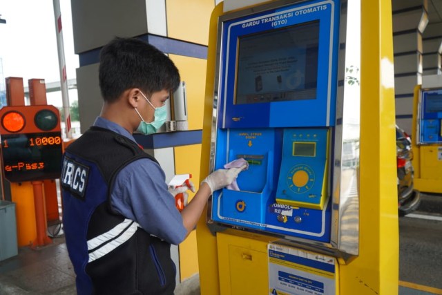 Petugas Jasa Marga membersihkan reader tapping uang elektronik di pintu tol. Foto: Jasa Marga