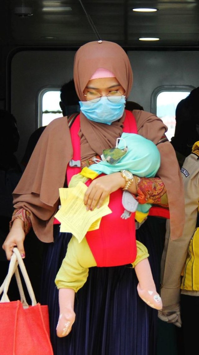 Seorang penumpang kapal menggendong anaknya tiba di Pelabuhan Internasional PT Pelindo I Dumai dari Melaka, Malaysia Foto:  ANTARA FOTO/Aswaddy Hamid