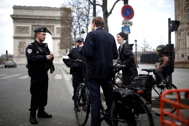 Petugas kepolisian Prancis memeriksa pengendara sepeda di depan Arc de Triomphe yang sepi saat lockdown di Paris, Prancis. Foto: REUTERS / Benoit Tessier