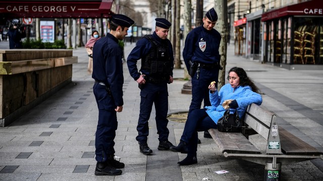 Polisi merazia seorang wanita yang sedang duduk di bangku jalan Champs-Elysees di Paris, Prancis. Foto: AFP/Martin BUREAU