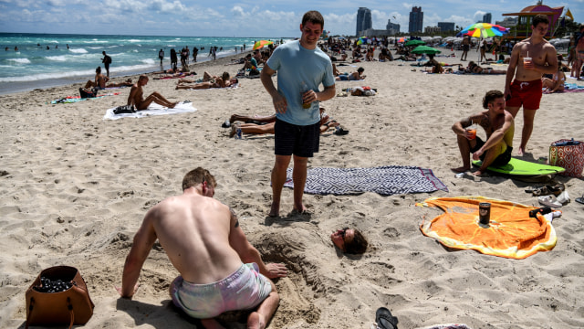 Pengunjung berjemur dan bermain pasir di Pantai Miami, Florida, Amerika Serikat. Foto: AFP/CHANDAN KHANNA