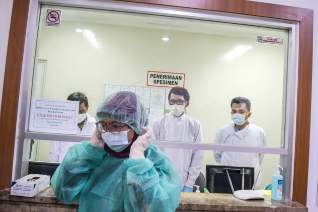 Petugas mengenakan pakaian steril saat akan memasuki Laboratorium Balitbangkes, Jakarta. Foto: ANTARA/Galih Pradipta