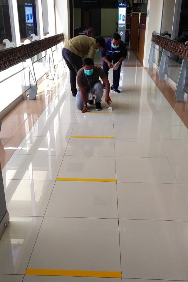 Petugas di Bandara Sultan Iskandar Muda memasang garis kuning berjarak 1 meter penanda batas antar penumpang. Foto: Dok. PT AP II