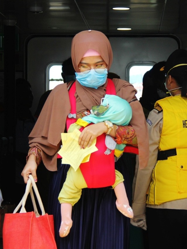 Seorang penumpang kapal menggendong anaknya tiba di Pelabuhan Internasional PT Pelindo I Dumai dari Melaka, Malaysia, Rabu (18/3/2020). Foto: Antara/Aswaddy Hamid