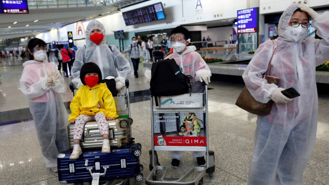 Sejumlah penumpang menggunakan pakaian pelindung dari plastik di Bandara Internasional Hong Kong, Hong Kong, Selasa (17/3). Foto: REUTERS/Tyrone Siu