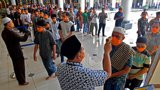 Umat muslim mengenakan masker mengantri memeriksakan suhu tubuh ketika memasuki Masjid Nasional Al Akbar Surabaya untuk melaksanakan shalat Jumat, Surabaya. Foto: ANTARA FOTO/Zabur Karuru