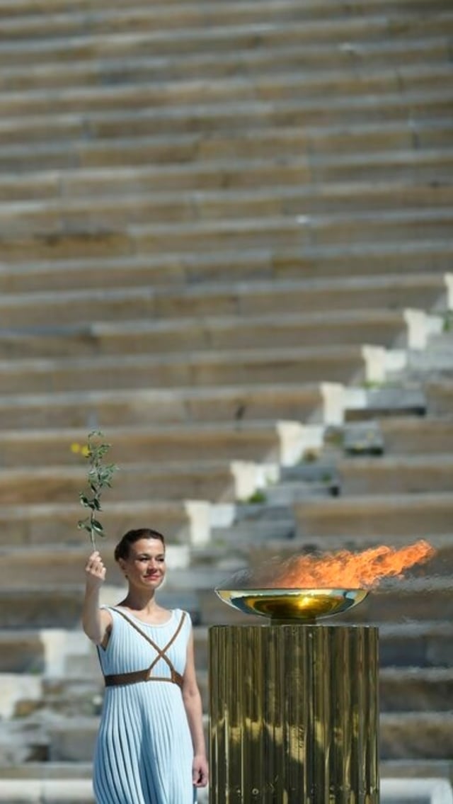 Koreografer Artemis Ignatiou berdiri di sebelah nyala api Olimpiade selama upacara penyerahan nyala api Olimpiade 2020 di Athena, Kamis (19/3). Foto: Aris Messinis/Pool via AP