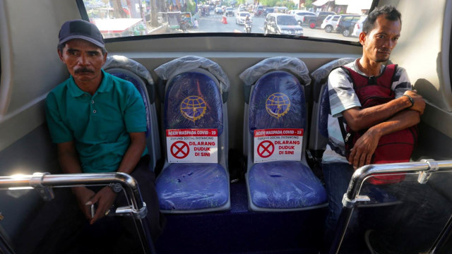 Penumpang duduk diantara kursi yang telah ditandai larangan duduk jarak sosial (Social Distancing) di dalam bus trans kutaraja, Banda Aceh, Aceh.  Foto: ANTARA FOTO/irwansyah Putra