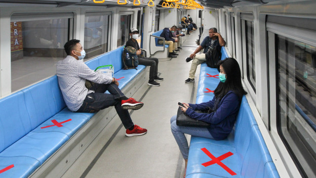 Penumpang duduk di bangku yang telah diberi stiker panduan jarak antarpenumpang di rangkaian gerbong kereta LRT, Palembang. Foto: AFP/Abdul QODIR