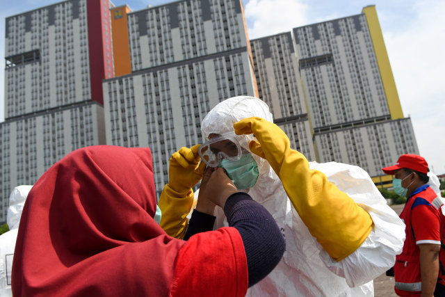 Petugas PMI memakai kacamata pelindung untuk melakukan penyemprotan cairan disinfektan pada Wisma Atlet di Kemayoran, Jakarta, Sabtu (21/3). Foto: ANTARA/M. Risyal Hidayat