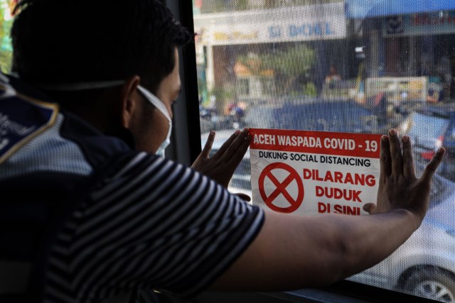 Petugas Dishub Aceh menempelkan stiker tanda larangan duduk jarak sosial (social distancing) dalam bus Trans Koetaradja. Foto: Irfan Fuadi-Humas Dishub Aceh
