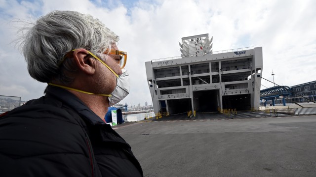 Seorang pria menggunakan masker melihat kapal pesiar Splendid yang akan digunakan sebagai rumah sakit sementara pasien virus corona di Genoa, Italia.  Foto: REUTERS / Massimo Pinca