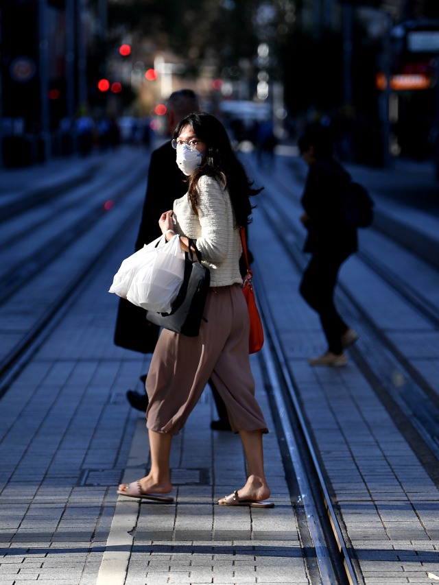 Warga menggunakan masker berjalan di sebuah jalan di Sydney, Australia.  Foto: AFP/Saeed KHAN
