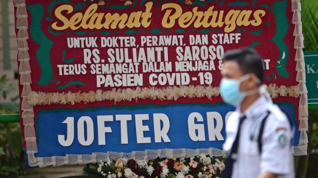 Petugas berjalan di samping karangan bunga dukungan untuk tenaga medis dan staf Rumah Sakit Penyakit Infeksi (RSPI) Sulianti Saroso di Jakarta Foto: ANTARA FOTO/Aditya Pradana Putra