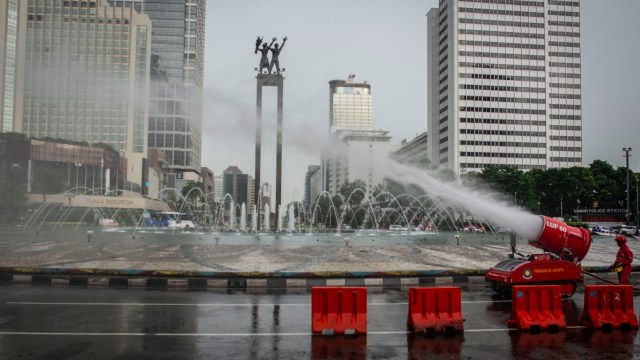 Petugas Damkar menyemprotkan cairan disinfektan di kawasan Bundaran HI, Jakarta. Foto: ANTARA FOTO/Aprillio Akbar