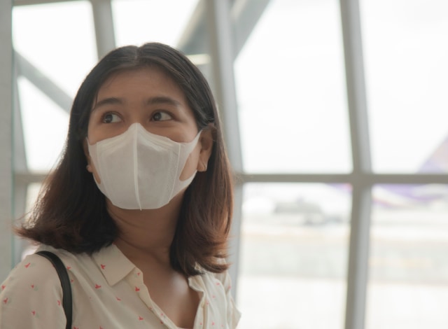 Ilustrasi penumpang wanita mengenakan masker saat berada di bandara Foto: Shutter Stock