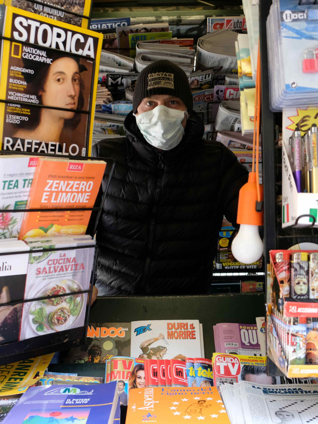 Penjual koran dan majalah di Italia yang masih buka di tegah ancaman virus corona. Foto: REUTERS/Manuel Silvestri